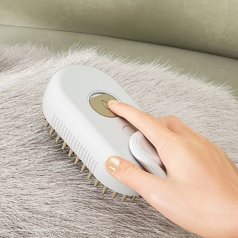 A hand pressing a button on a grey, handheld pet grooming brush with silicone bristles resting on grey fur.