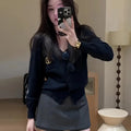 Woman wearing a navy blue V-neck button-down cardigan with gold detail, paired with a dark grey mini skirt.