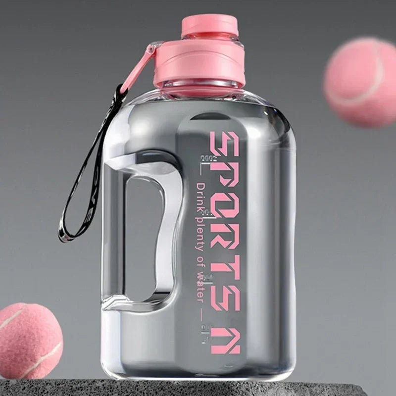 Clear sports water bottle with a pink lid, handle, and "SPORTS" text, displayed with pink tennis balls.