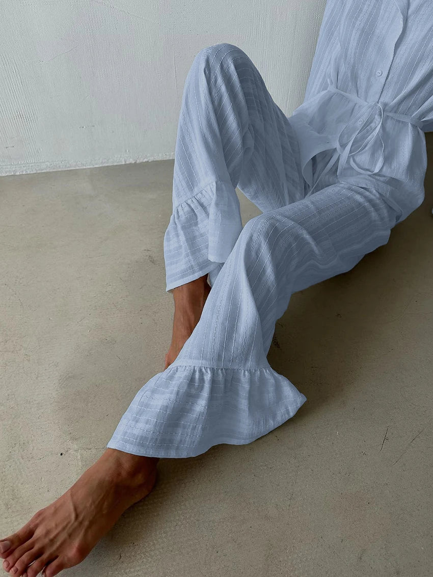 White striped pyjama set with button-up shirt and wide-leg trousers featuring ruffle-hem details.