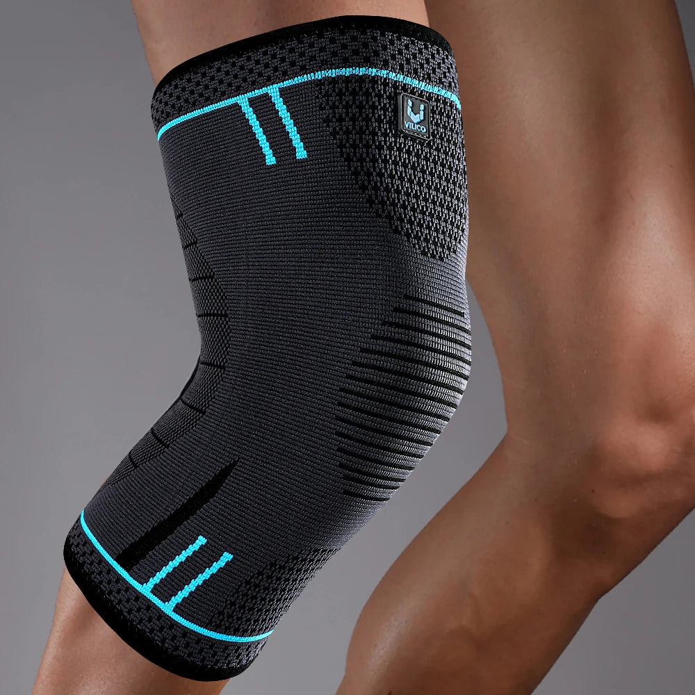 A charcoal grey elasticated knee support sleeve with bright blue accents worn on a leg.