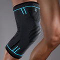 A charcoal grey elasticated knee support sleeve with bright blue accents worn on a leg.