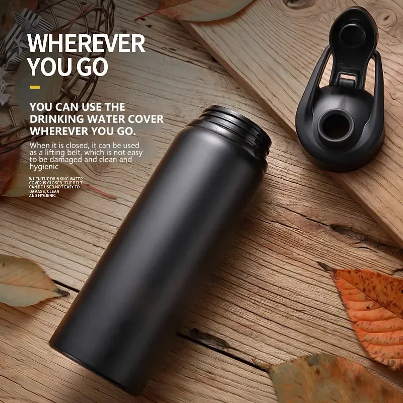 Matte black reusable water bottle with a detached flip-top lid, shown on a rustic wooden surface.