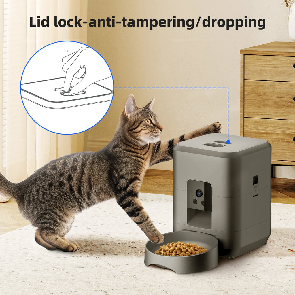 Grey automatic pet feeder with a camera, tamper-proof lid lock, and bowl, shown with a cat reaching for the food.