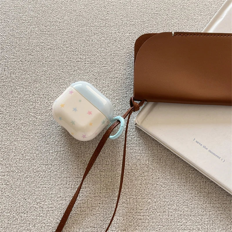 Light blue and white AirPods case with a colourful star print, featuring a pastel blue carry ring.
