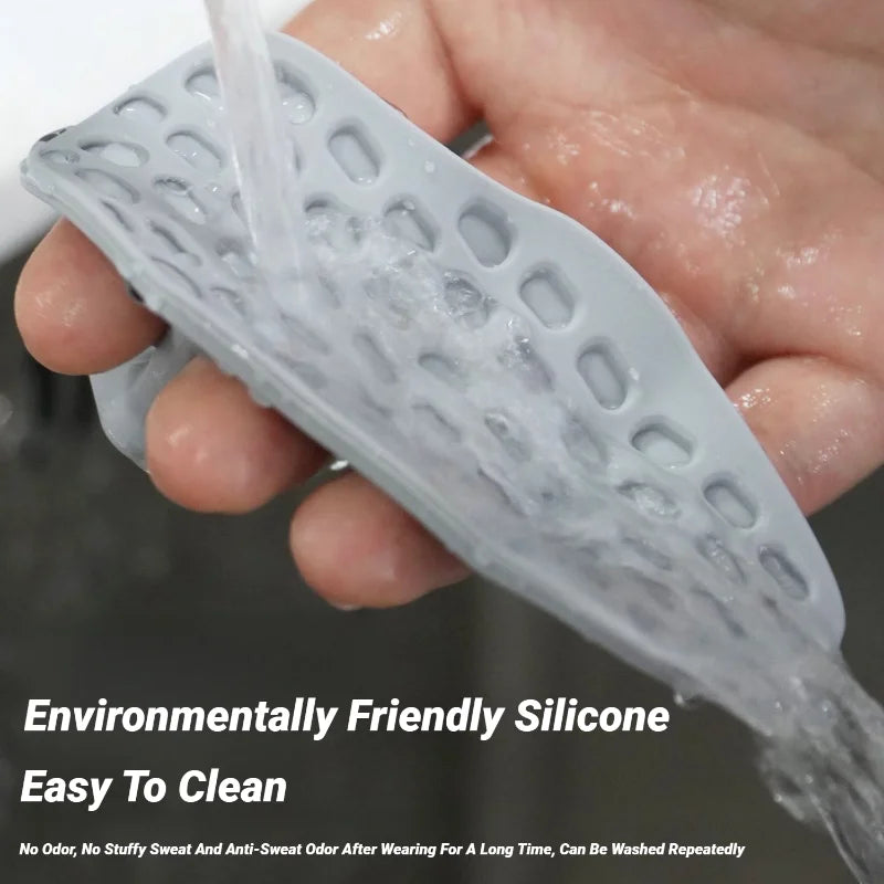 A grey, flexible silicone watch strap with a perforated, breathable design being rinsed under a tap.