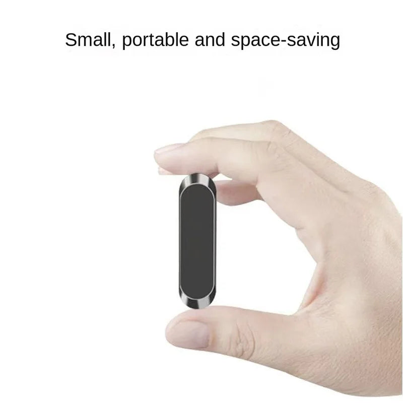 A small, portable, pill-shaped black magnetic phone mount held between two fingers.
