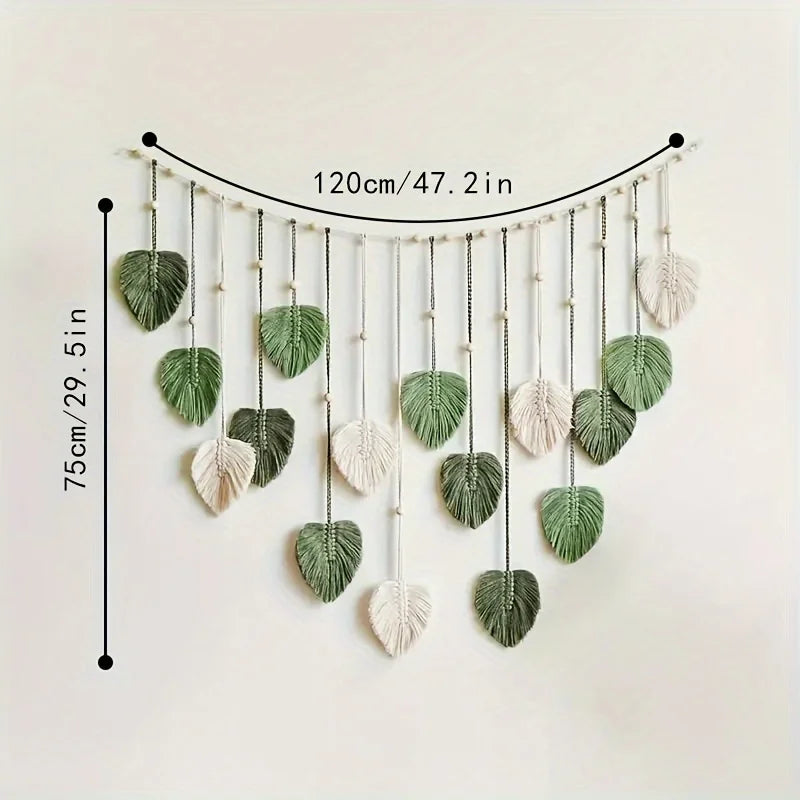 Boho macrame wall hanging featuring sage green and cream leaf-shaped tassels suspended on a beaded string.