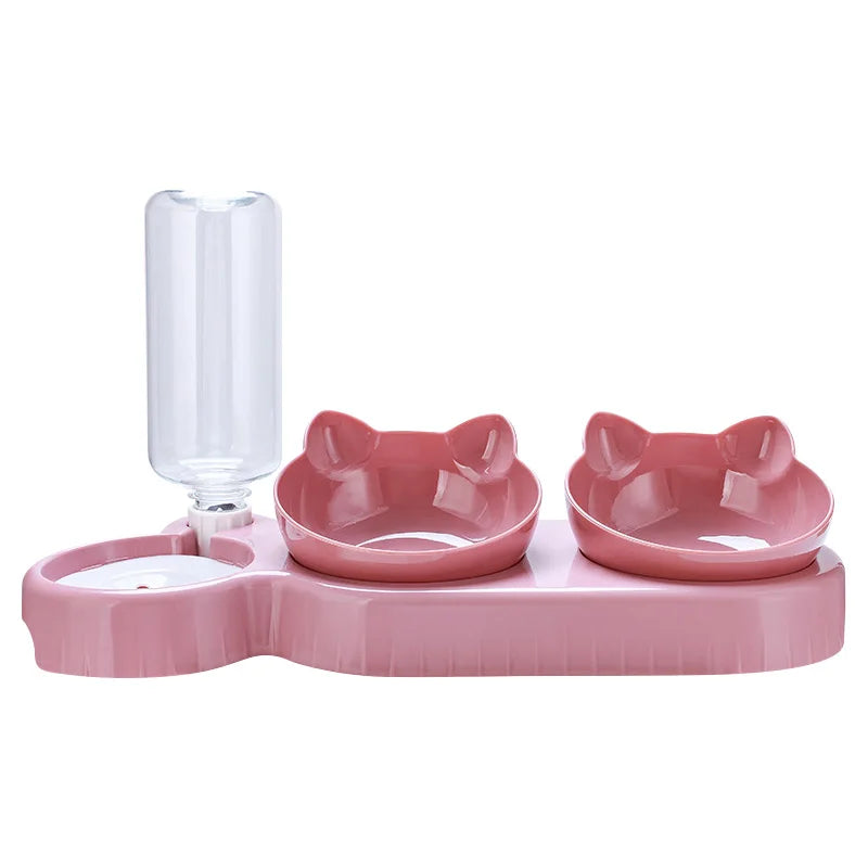 Pink pet feeder station with two cat-shaped bowls and an integrated clear water bottle on a white background.