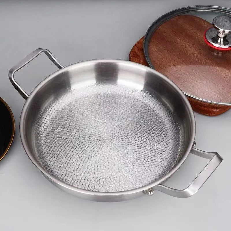 Stainless steel frying pan with double side handles and textured honeycomb interior, accompanied by a glass lid.
