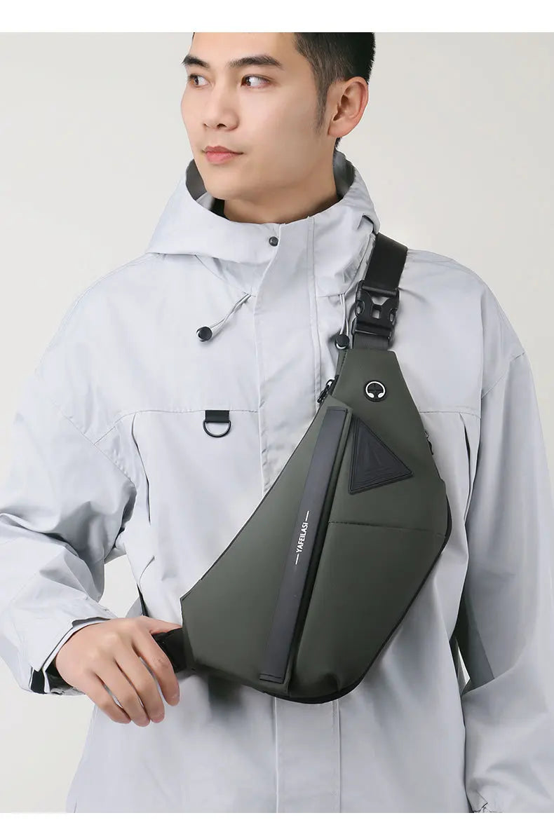 A man wearing an olive green anti-theft crossbody sling bag with a secure buckle strap and headphone port.