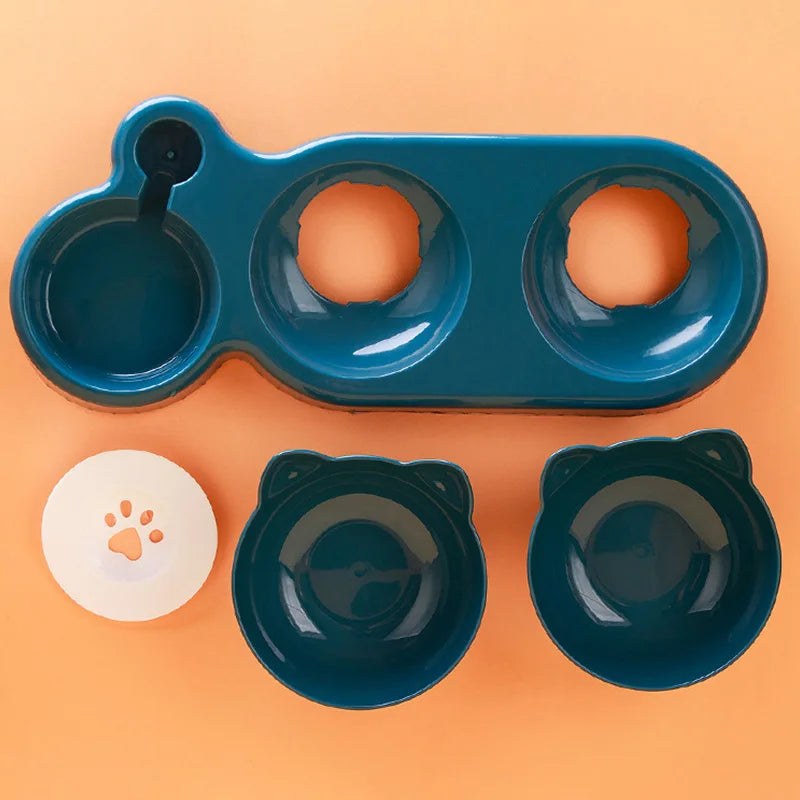 Teal pet feeding station with two cat-ear shaped bowls, a base tray, and a small white paw-print disc.