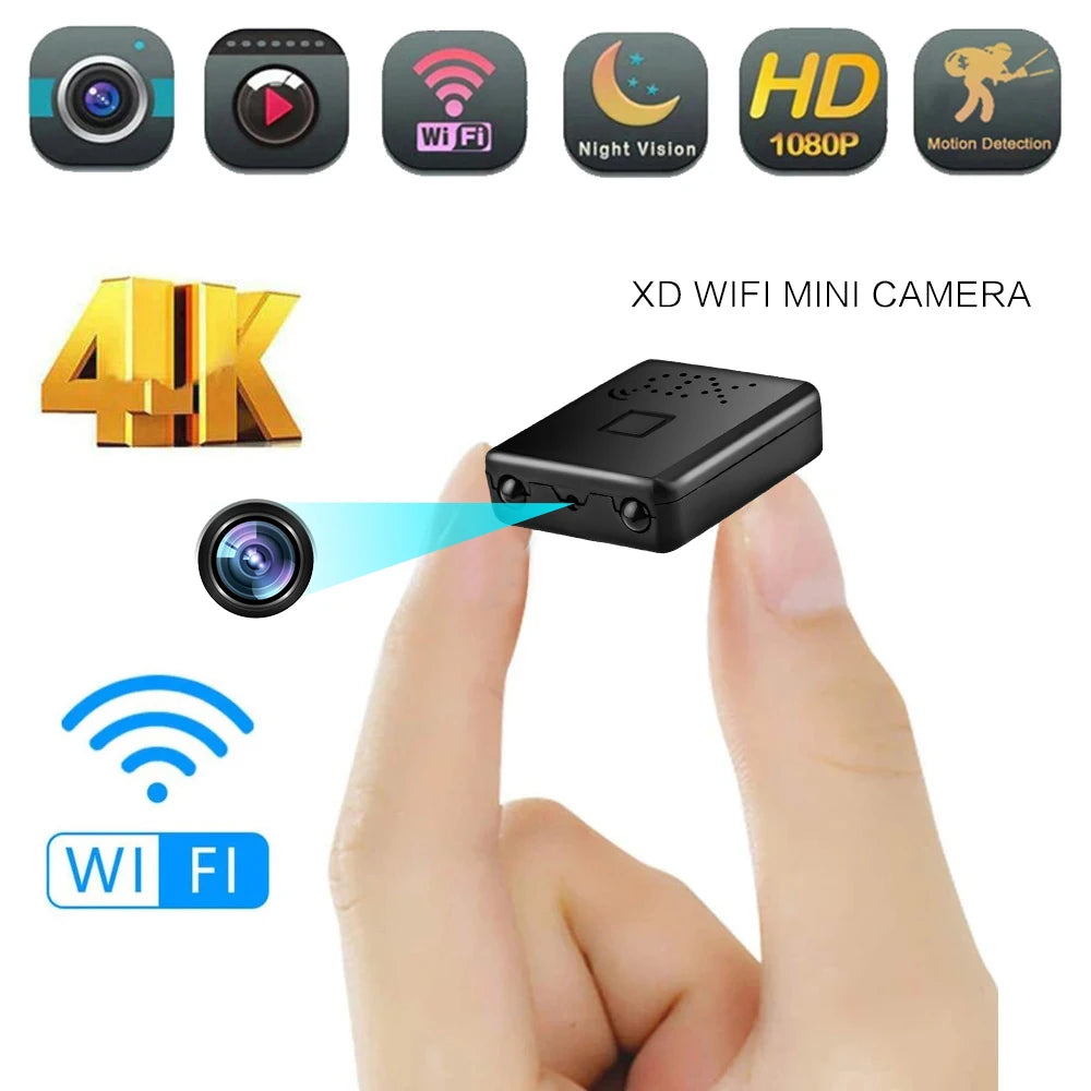 Black plastic mini WiFi camera held between fingers, featuring night vision, motion detection, and 4K recording.