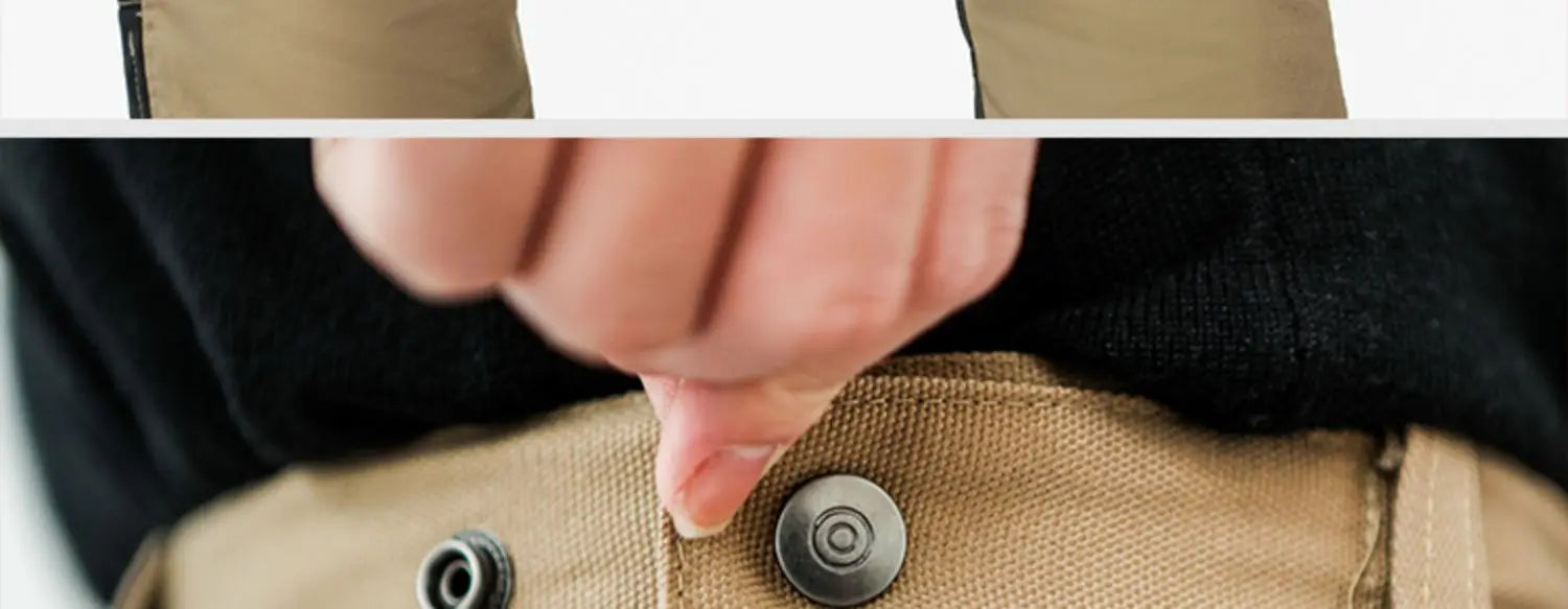 Close-up of a person fastening the metal button on tan cotton cargo work trousers.