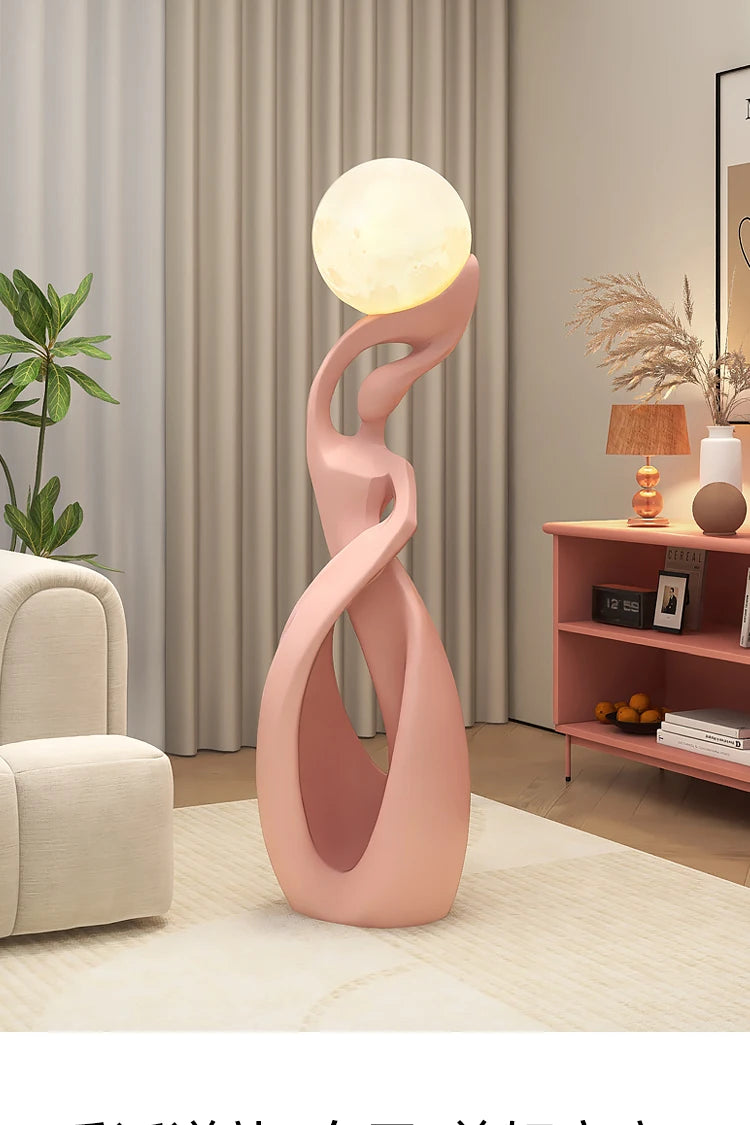 Tall, abstract pink floor sculpture featuring a smooth, curved design and a glowing, moon-like orb on top.