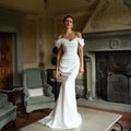 White satin mermaid wedding dress with off-the-shoulder sweetheart neckline and fitted bodice.