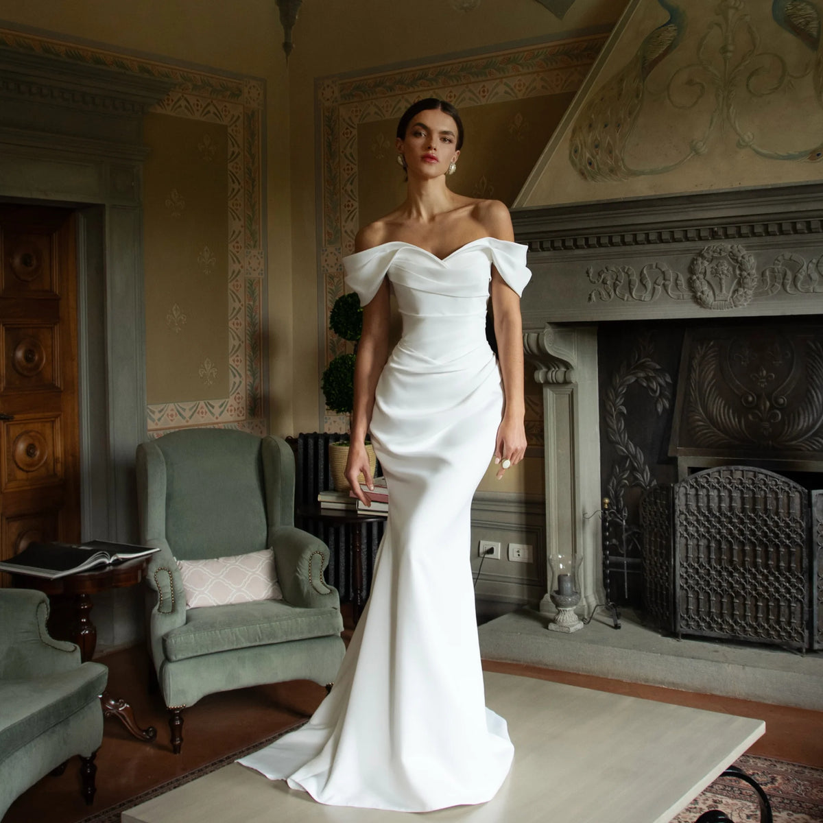 White satin mermaid wedding dress with off-the-shoulder sweetheart neckline and fitted bodice.