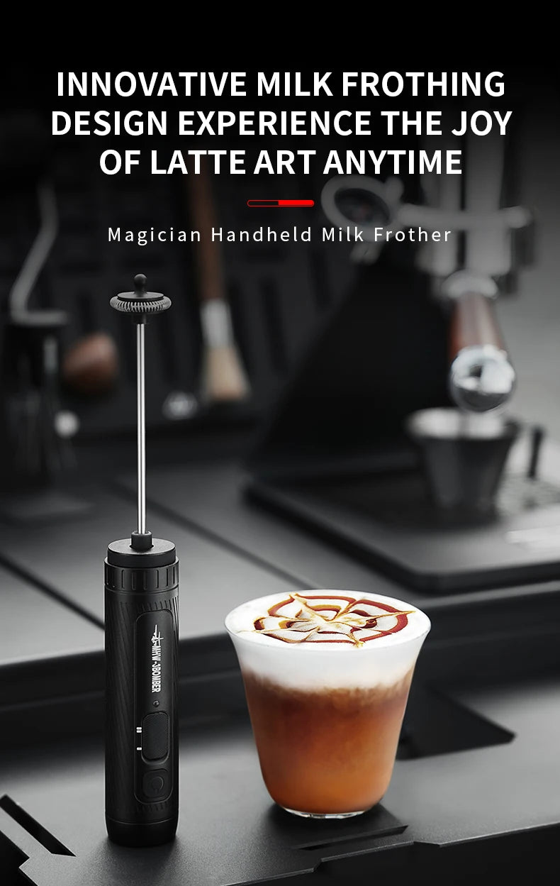 A sleek, matte black handheld electric milk frother with a long metal whisk stem, placed next to a cup of latte art.