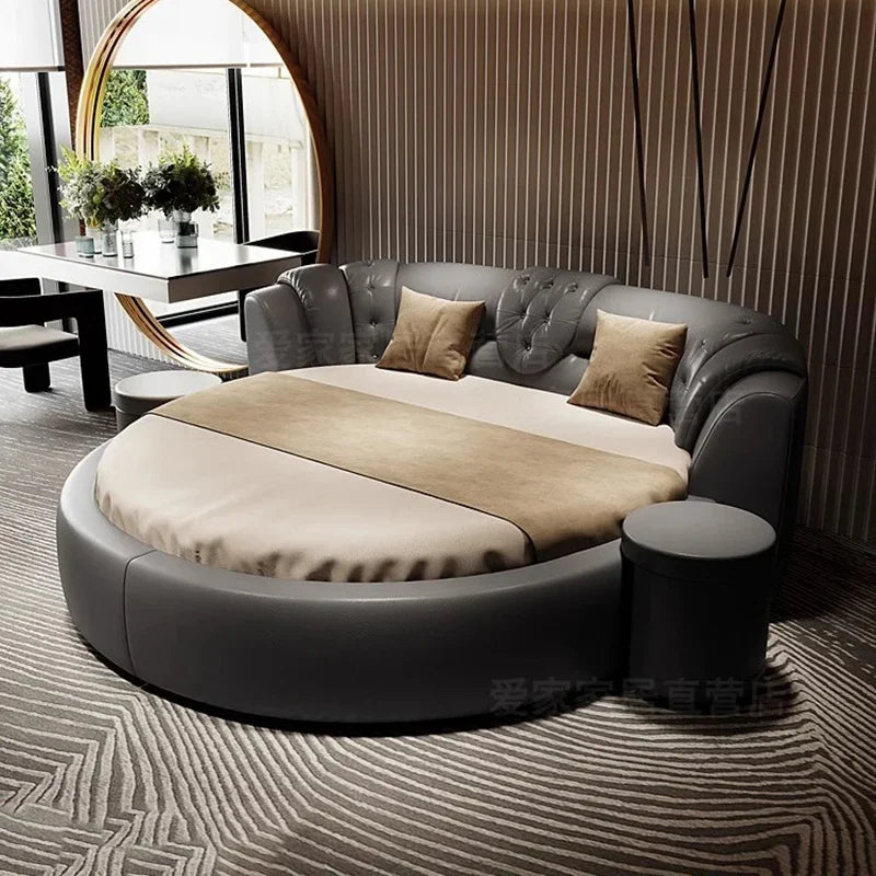 Modern luxury round double bed in grey leather with tufted backrest, beige bedding, and a matching circular stool.