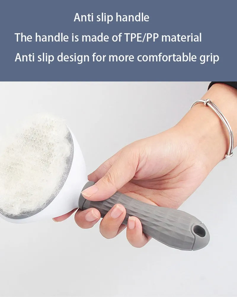 A hand holding a pet grooming slicker brush with a white head and a grey, textured non-slip rubber handle.