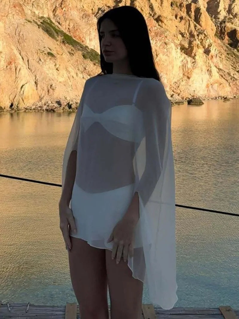 White sheer beach cover-up with long, flowing sleeves, worn over a matching white bikini set.