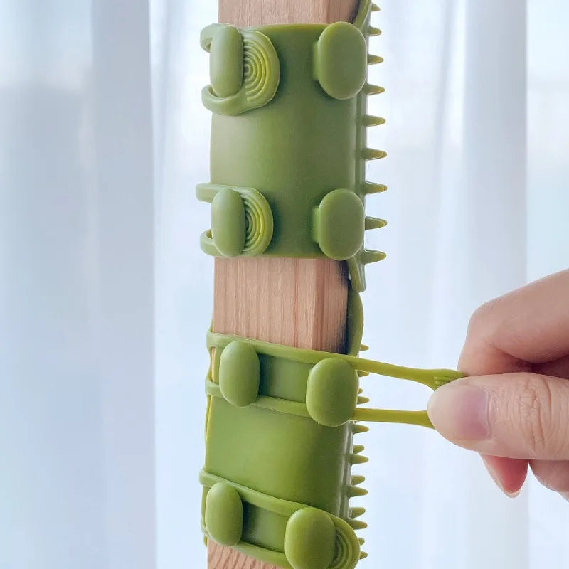 A green silicone cable-tie organiser wrap being secured around a wooden furniture leg by a hand.