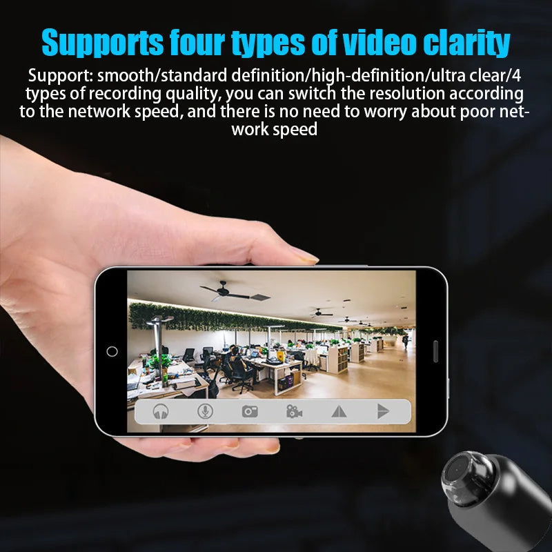 Hand holding a smartphone displaying a security camera feed from a black plastic wireless camera.