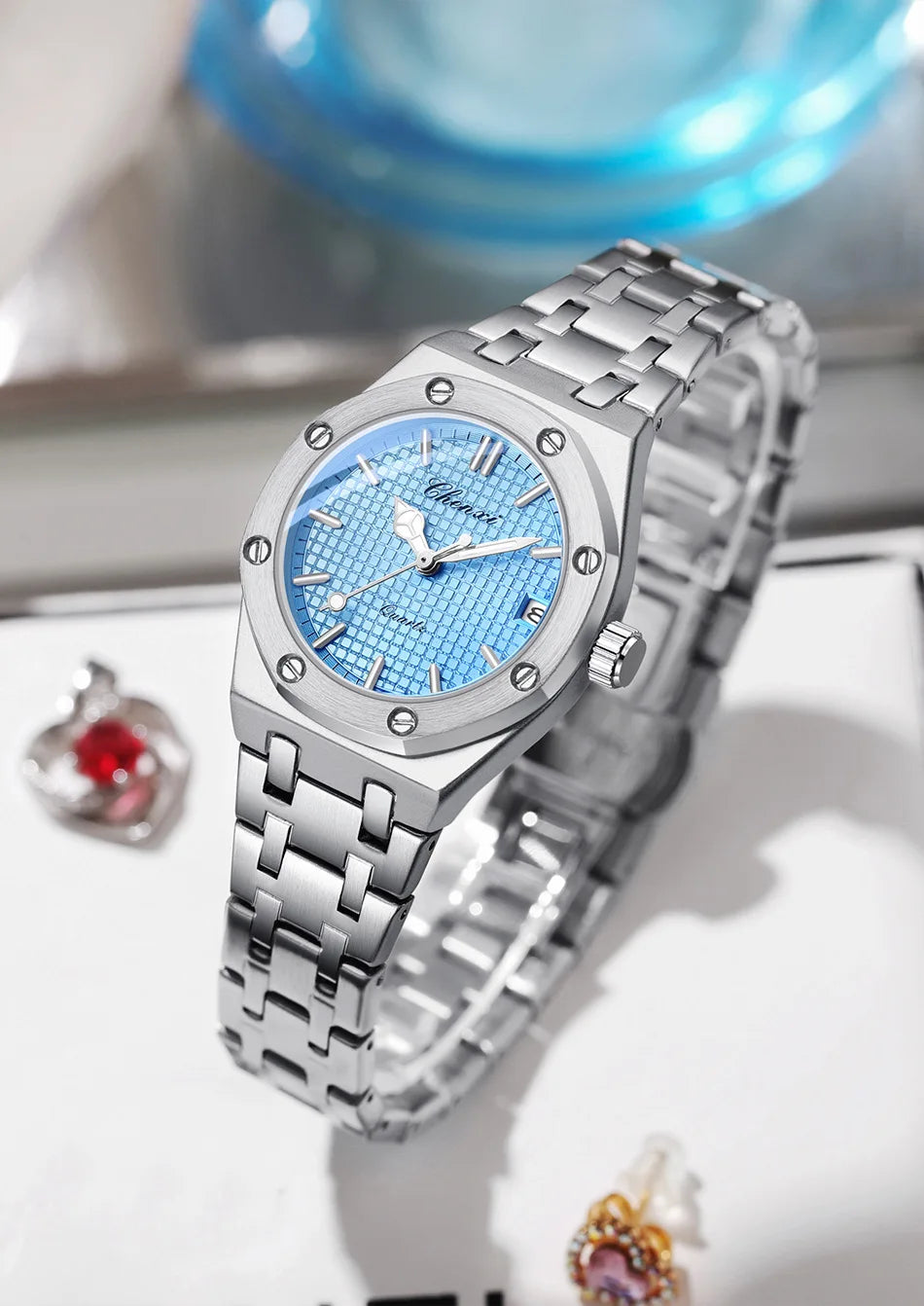 Luxury women's analogue watch in silver stainless steel with a textured sky-blue dial and screw-detail bezel.