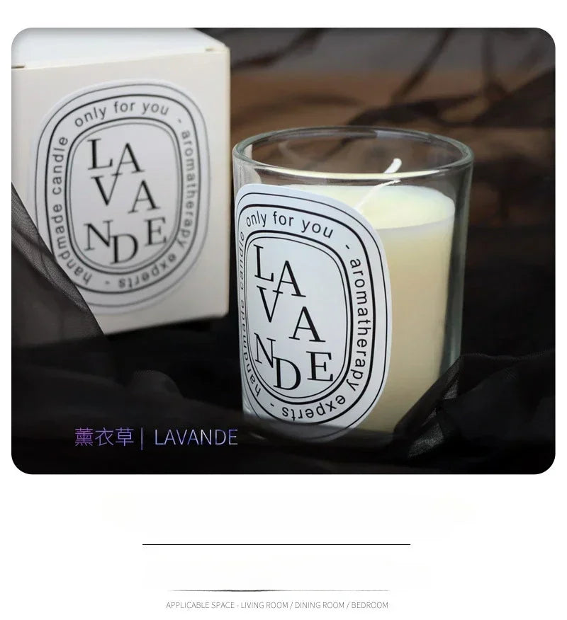 A scented lavender candle in a glass jar with a white label, next to its matching cream-coloured gift box.