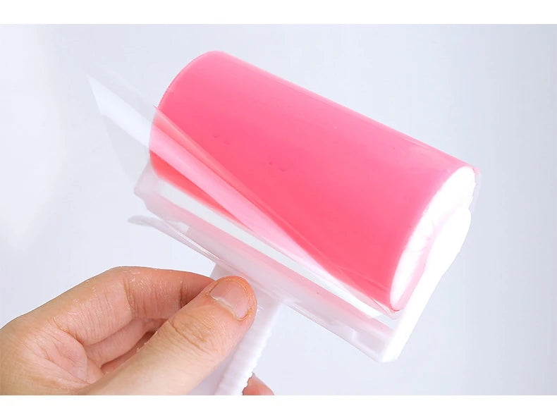 Handheld lint roller with a bright pink, reusable adhesive drum and a white plastic handle.