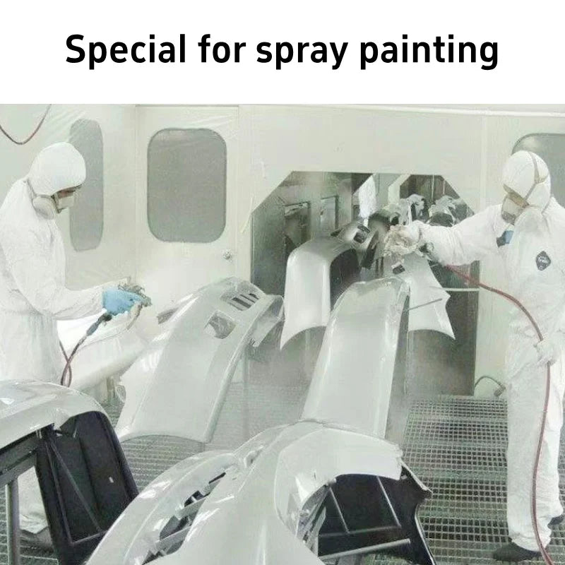Two people in white protective suits spray paint grey plastic car bumpers in a ventilated booth.
