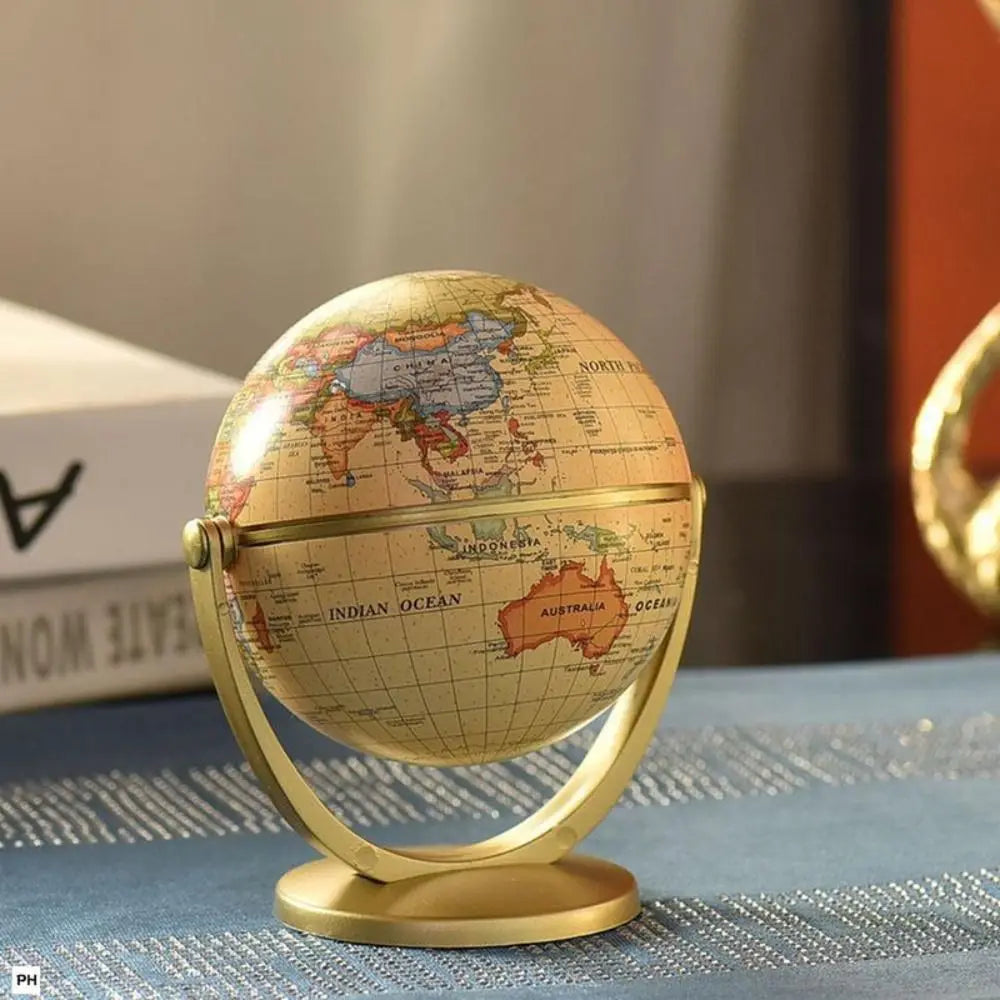 Vintage-style desk globe with a beige map and gold-tone metal stand on a blue textured surface.