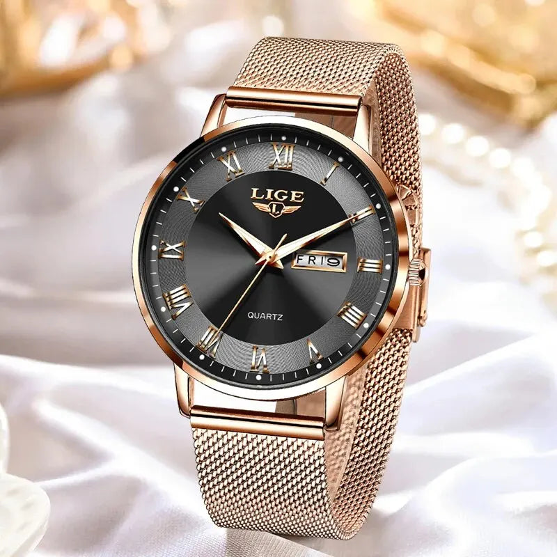 Elegant rose gold stainless steel watch with a black dial, Roman numerals, and a mesh bracelet strap.
