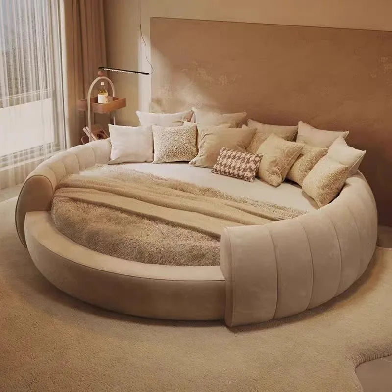 A minimalist, arched wooden bedside table with a sleek black lamp, styled next to a modern round cream bed.