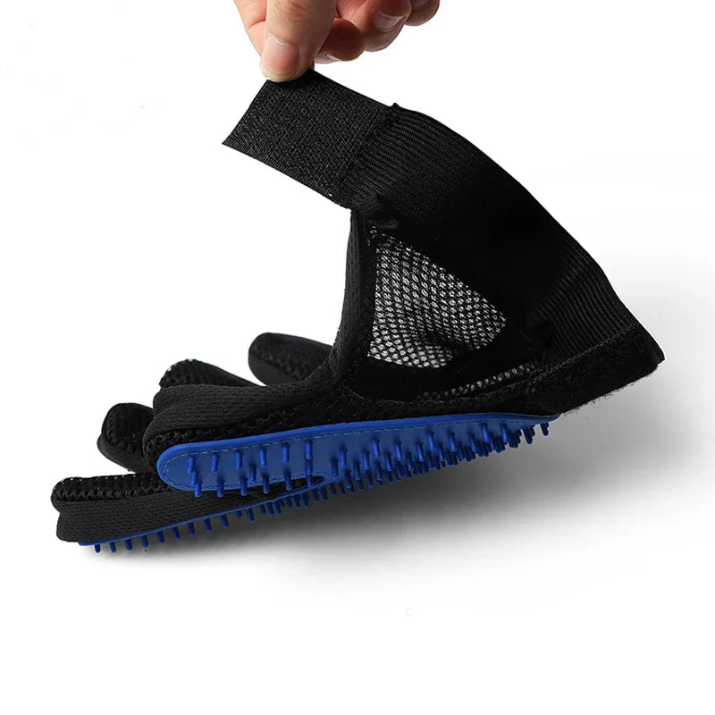 A black mesh grooming glove with a blue silicone bristled palm, held up against a plain white background.