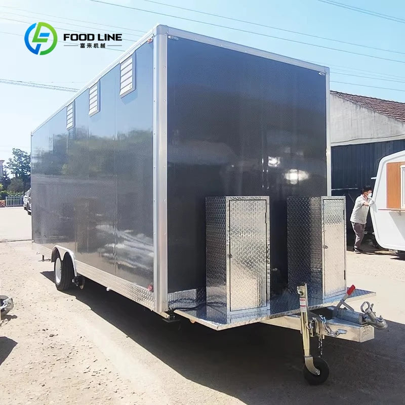 Large rectangular dark gray mobile food trailer with dual axles, a tongue jack, and dual diamond-plate storage boxes.