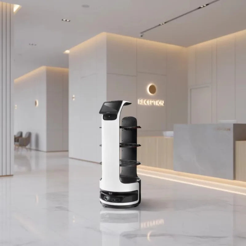 A white and black service robot with multiple shelves stands in a modern, brightly lit office lobby.