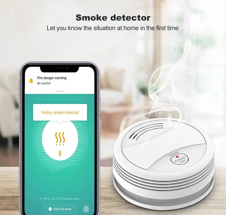 White round smoke detector next to a smartphone displaying a fire danger warning app notification.