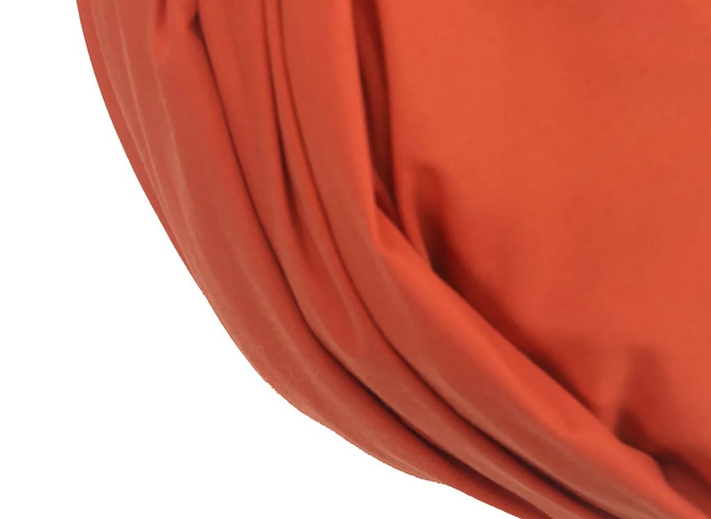 Close-up of a terracotta orange, French-style vintage turban hat featuring soft, draped fabric folds.