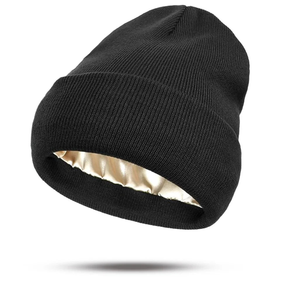 Black knitted beanie hat with a folded brim and a smooth champagne-coloured satin lining.