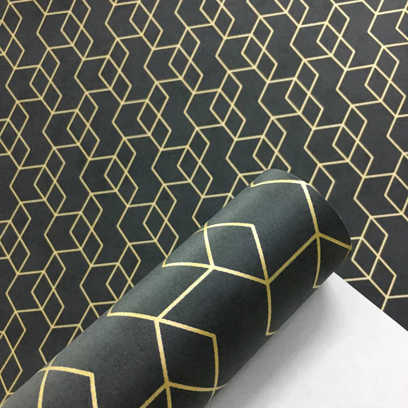 Modern wallpaper roll featuring a matte black background with a metallic gold geometric cube pattern.
