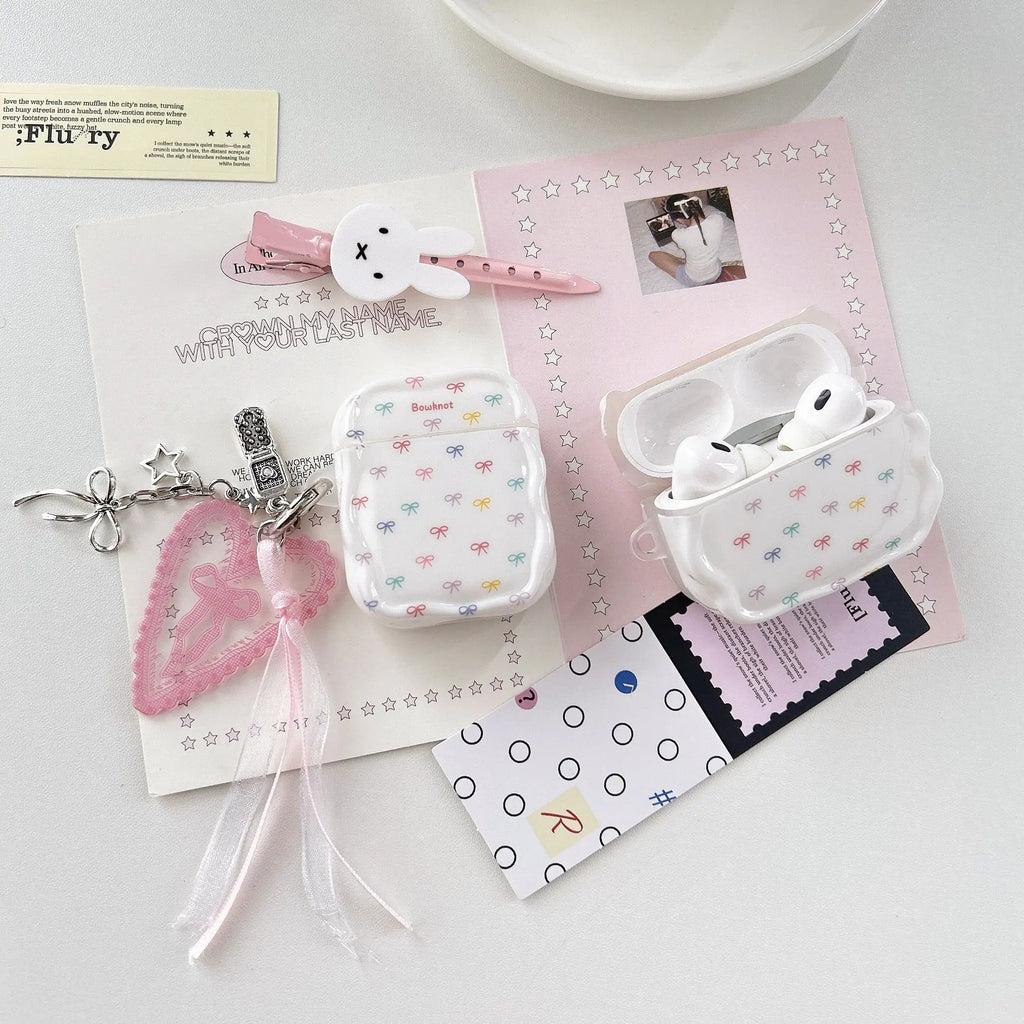 White glossy silicone AirPods case featuring a colourful bow print, complete with a heart-shaped charm accessory.