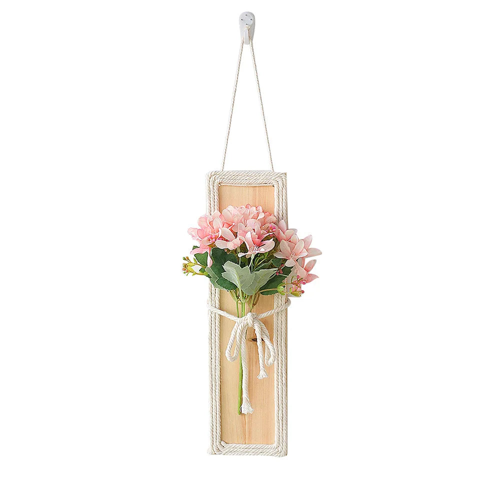 Bohemian-style wall hanging featuring a rectangular wooden board wrapped in cream rope with a pink floral bouquet.