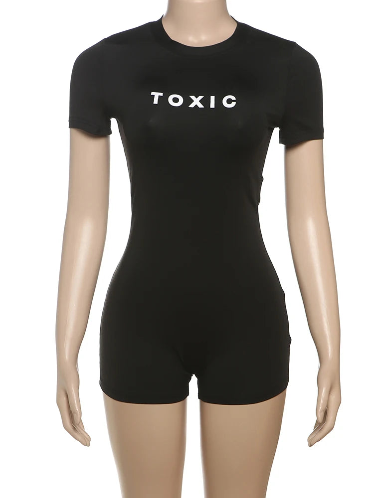 Black short-sleeve romper with a crew neck and "TOXIC" printed in white on the chest, worn on a mannequin.