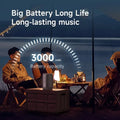 Compact grey Bluetooth speaker on a camping table, highlighting a 3000mAh battery for long-lasting music.