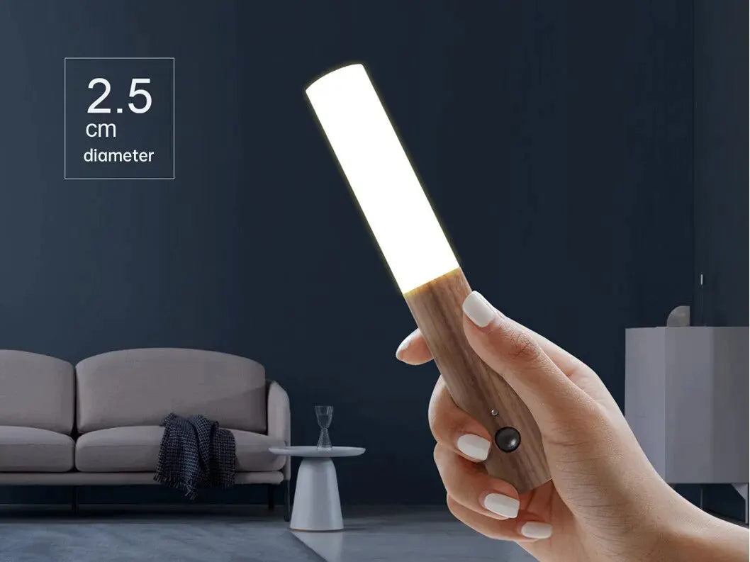 Slim, wood-effect rechargeable LED night light with a motion sensor held in a hand. Measures 2.5cm in diameter.
