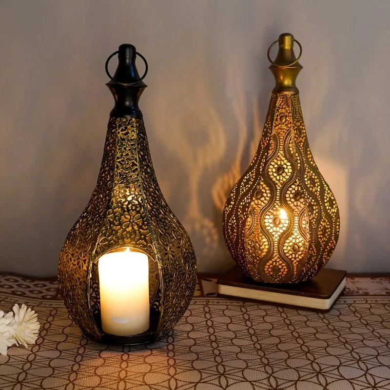 Two teardrop-shaped Moroccan iron lanterns with intricate cutouts, housing glowing pillar candles.