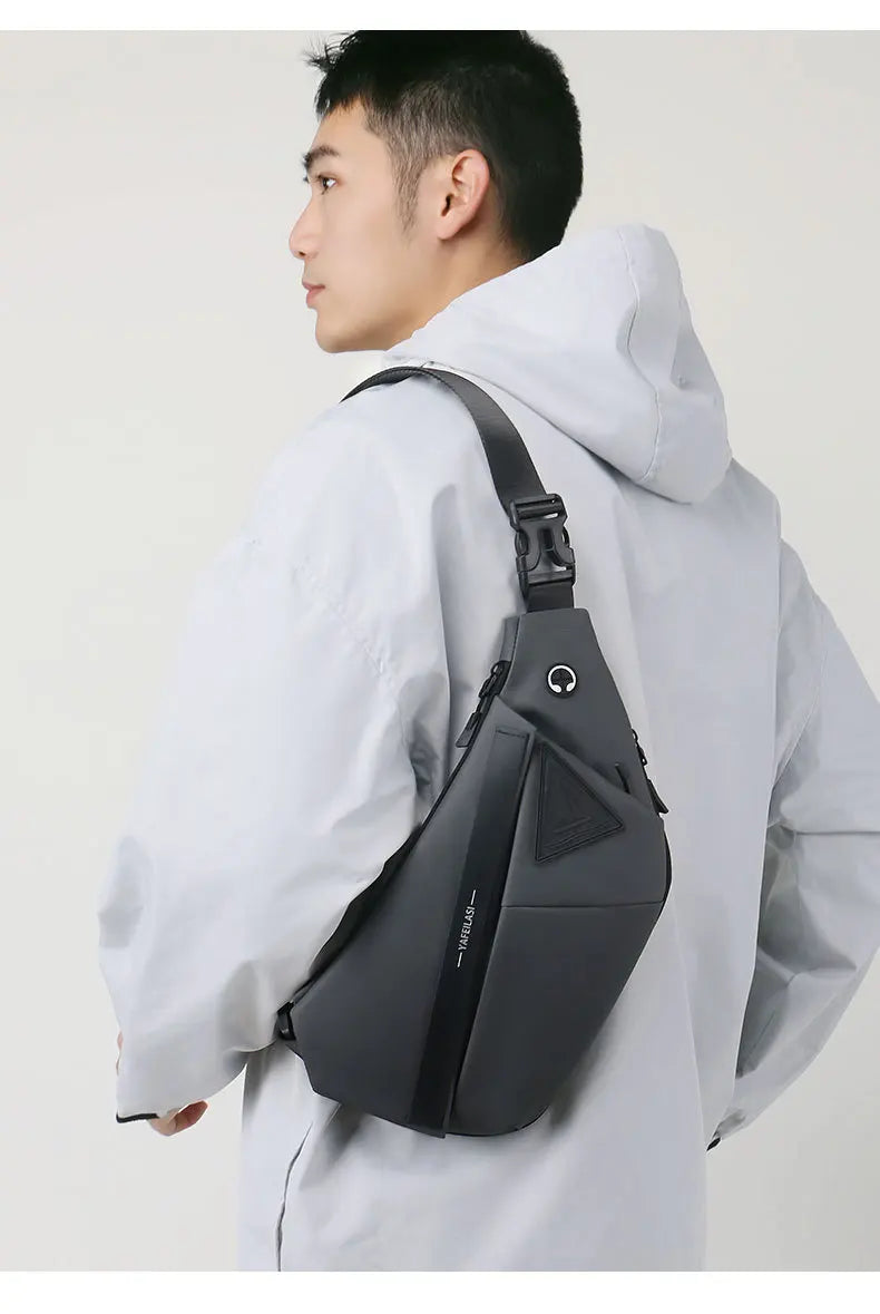 Grey men’s anti-theft crossbody sling bag with a secure buckle strap and headphone port.
