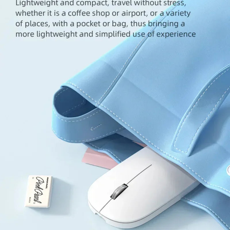 A slim, white, ergonomic wireless mouse tucked into a light blue bag next to a small eraser.