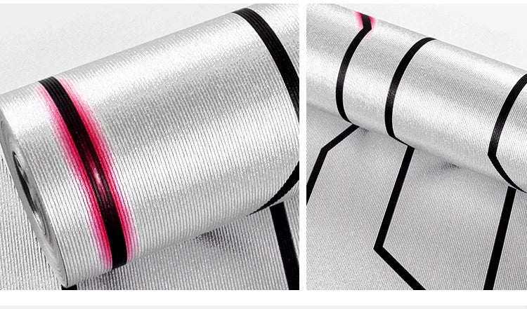 Modern silver reflective wallpaper roll with a textured surface, featuring black geometric lines and pink accents.
